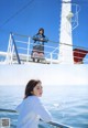 A woman standing on the deck of a boat looking out at the ocean.