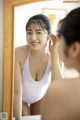 A woman in a pink bathing suit looking at herself in the mirror.