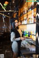 A woman standing in front of a bar holding a glass of wine.