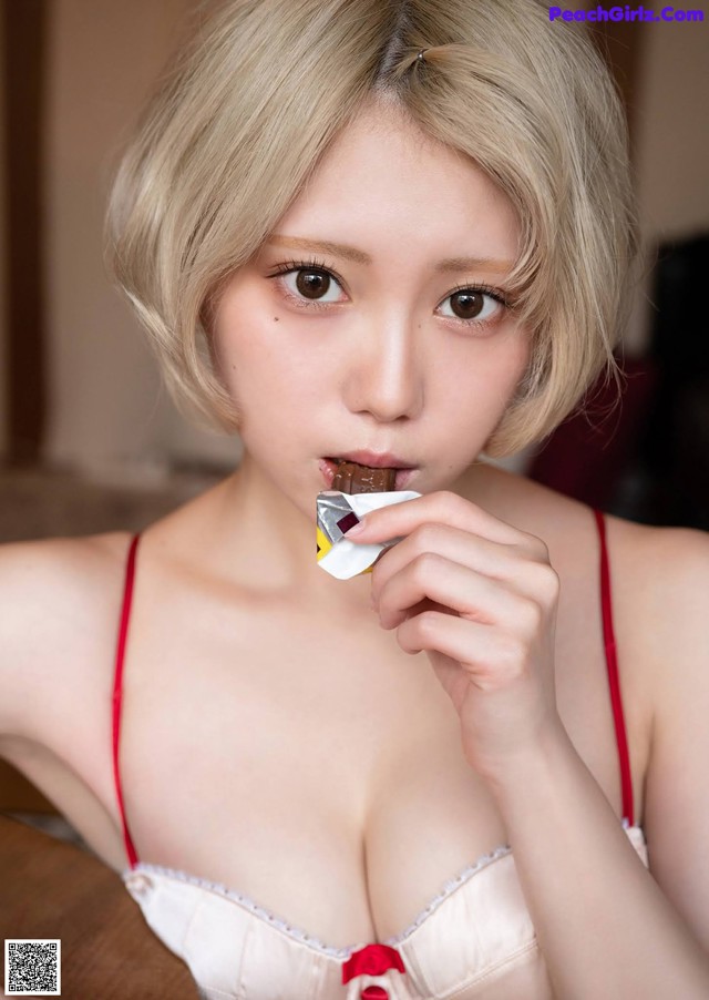 A woman in lingerie eating a piece of chocolate.