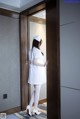 A woman in a white nurse outfit is opening a door.