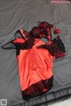 A red and black lingerie laying on a bed.