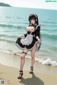 A woman in a maid outfit is standing on the beach.