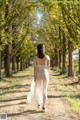 A woman in a white dress walking down a dirt road.