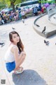 A woman sitting on the ground with pigeons around her.