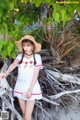 A woman in a white dress and straw hat posing for a picture.