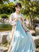 A woman in a blue and white hanbok is posing for a picture.