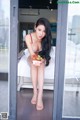 A woman sitting on a bed holding a bowl of strawberries.