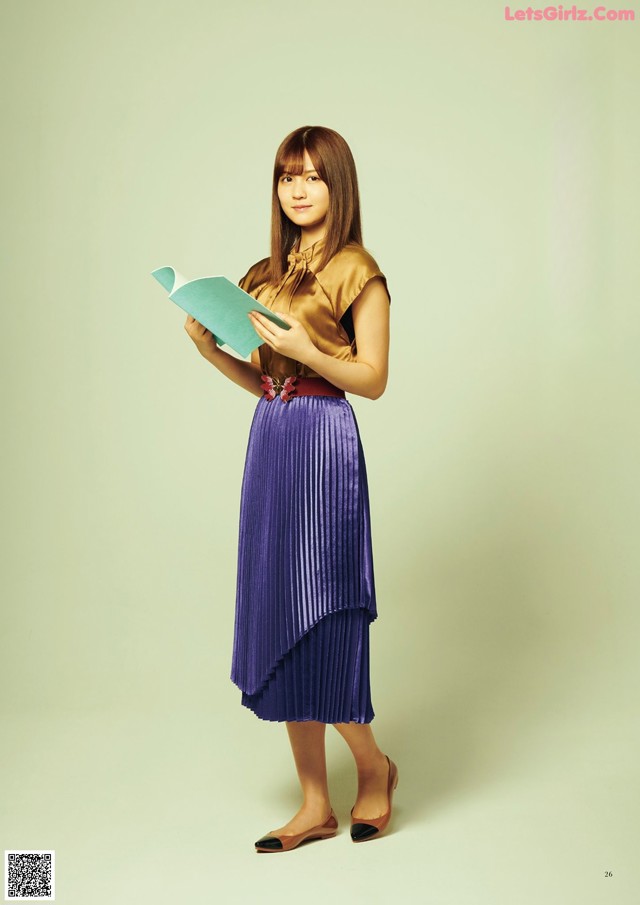 A woman in a purple pleated skirt holding a book.