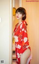 A woman in a red kimono standing in front of a door.