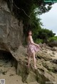 A woman standing on a rock on a beach.