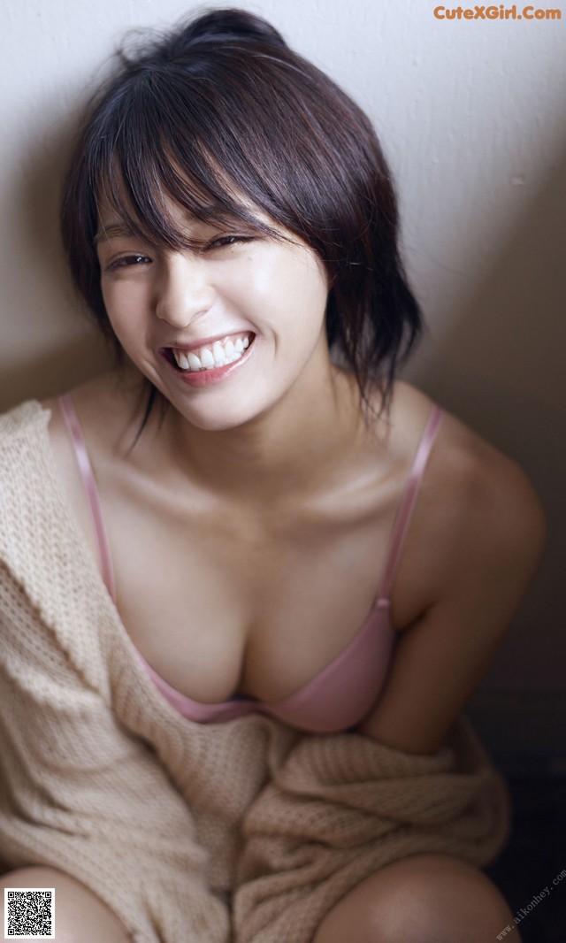 A woman in a pink bra sitting on the floor.