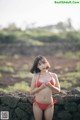 A woman in a red bikini standing on a stone wall.